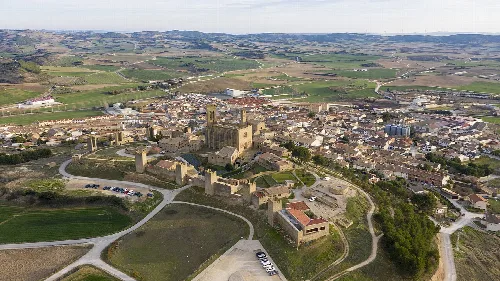 Vista aérea de un castillo y murallas en un pueblo rodeado de campos en Navarra.