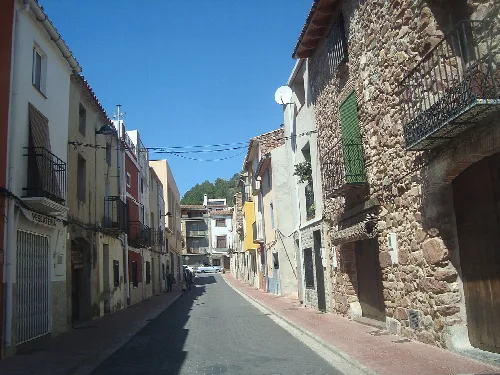 Calle estrecha con casas antiguas y balcones de hierro en La Pobla Tornesa.
