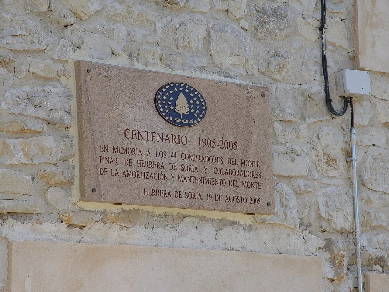 Placa conmemorativa del centenario de la compra del "Monte Pinar" de Herrera de Soria en la fachada del Ayuntamiento.