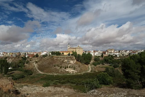 Landschaft mit Stadt und Kirche in Dosbarrios, Toledo, unter einem bewölkten Himmel.