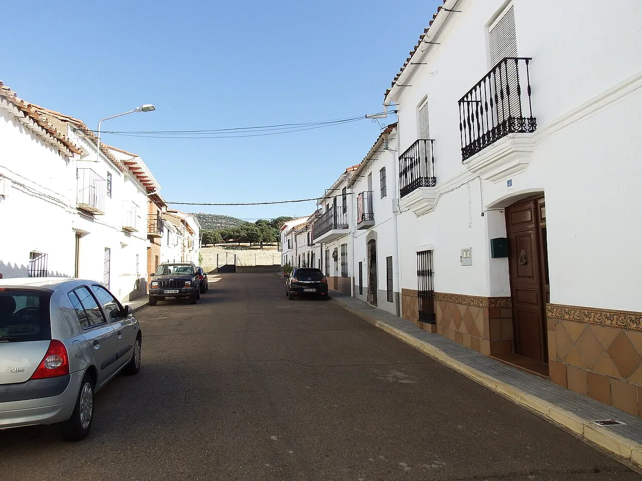 Calles con casas blancas y coches aparcados en Baterno.