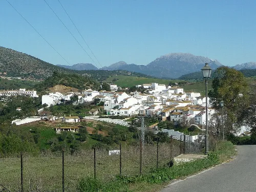 Weißes Dorf mit Häusern und Bergen im Hintergrund.