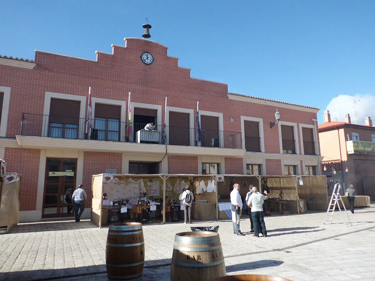 Town hall building in Villanueva de Duero with people and barrels in the square.