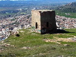 Torre Mathé in Puertollano, a stone structure on a hill with city view.