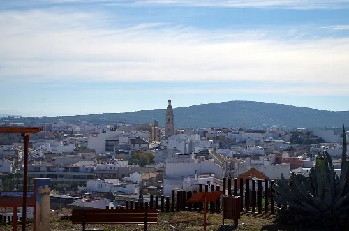 View of Aguilar de la Frontera with church and white rooftops, hills in the background.