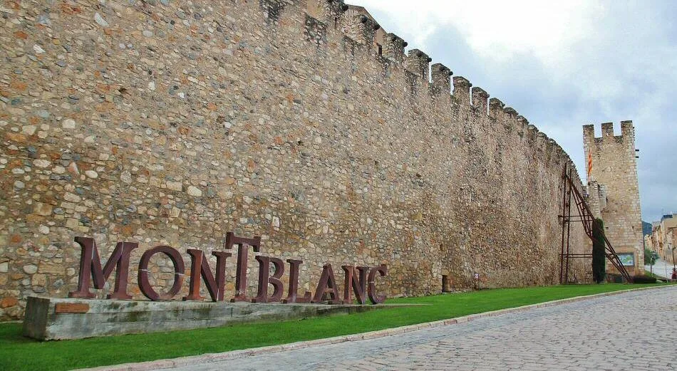 Mauerreste von Montblanc mit Schild und Rasen auf dem Santa Anna Platz.