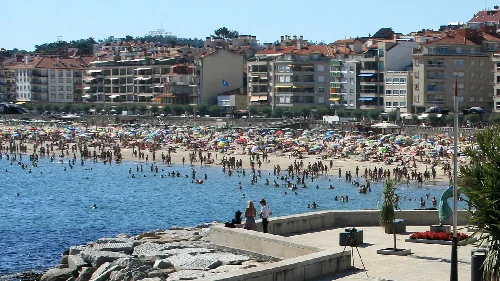 Playa del Silgar con gente en la arena y en el mar en Sanxenxo.