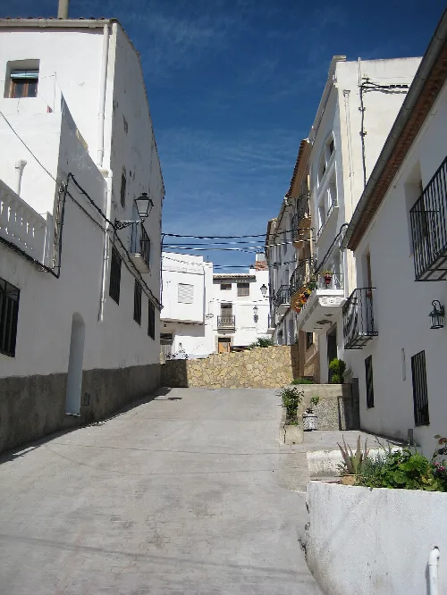 Enge Straße mit weißen Häusern und Eisenbalkonen in Vallat.