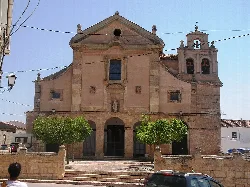 Fachada de piedra del convento con dos árboles en la plaza frente a la entrada.