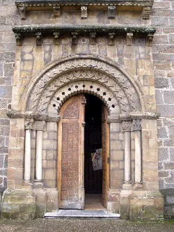 Puerta de piedra y madera con arco decorado en la iglesia de Santa Eulalia en Ujo.