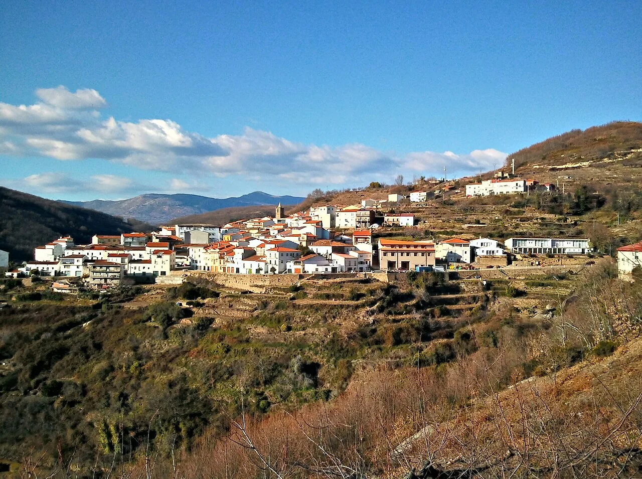Landschaft von Barrado mit weißen Häusern auf Hügeln und blauem Himmel mit Wolken.