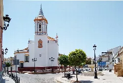 White church with tower and trees in Pilas square.