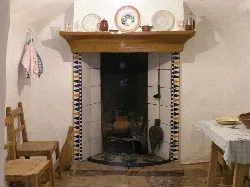 Stone fireplace in a traditional house with utensils on the mantel.