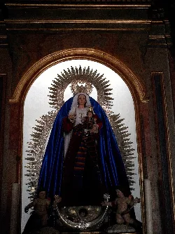 Imagen de la Virgen del Rosario con un manto azul y un fondo dorado en la iglesia.