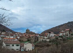 View of stone houses in Isaba with mountains and cloudy sky.