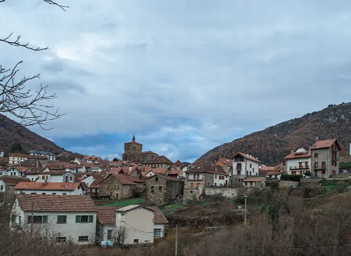 Vista de casas de piedra en Isaba con montañas y cielo nublado.