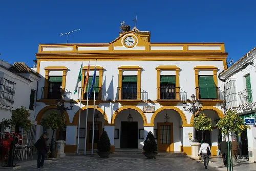 Rathaus mit weißer Fassade und gelben Details in La Puebla de Cazalla.