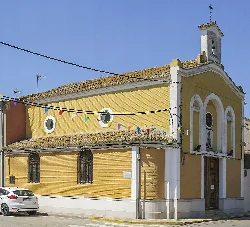 Yellow chapel facade with small bell tower and round windows.