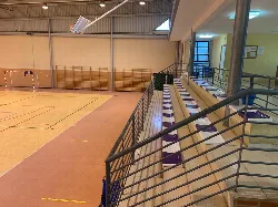 Innenansicht eines Sportzentrums mit Tribünen und einer Hallensportfläche.