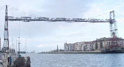 Puente de Vizcaya sobre el río con edificios a su lado.