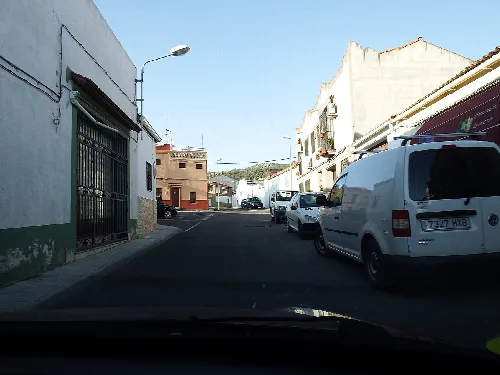Straße in Navalvillar de Pela mit Gebäuden und geparkten Autos.