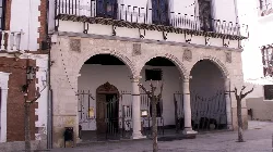 Fassade eines Gebäudes mit Bögen und Bäumen auf dem Platz in Baza.