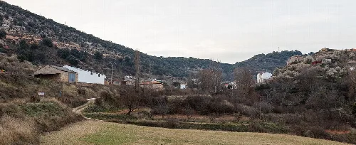 Rural landscape with scattered houses, trees, and hills in Castejón de Henares.