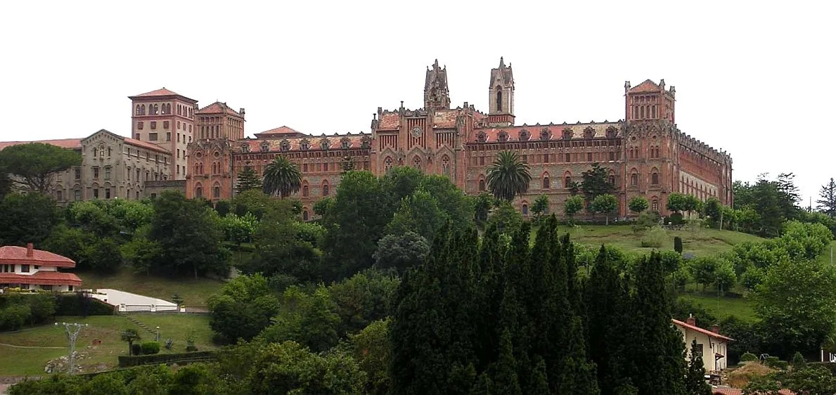 Universitätsgebäude auf einem Hügel mit Bäumen und Vegetation.