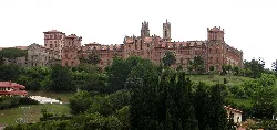 Universitätsgebäude auf einem Hügel mit Bäumen und Vegetation.