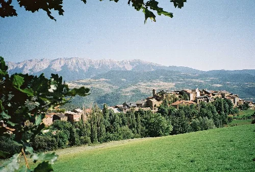Landschaft von Estamariu mit Häusern und Bergen im Hintergrund.