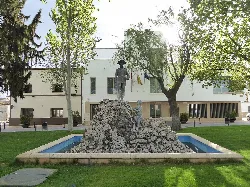 Sculpture in a fountain with trees and buildings in the background.