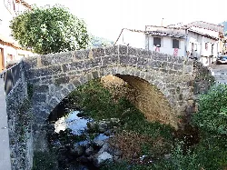 Steinbrücke über einem Fluss mit Vegetation in Tornavacas.