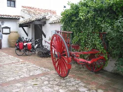 Red wooden cart with greenery and bicycles in Alfarnate, Málaga.