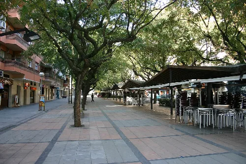 Eine Fußgängerstraße mit Bäumen und Barterrassen in Viladecans.