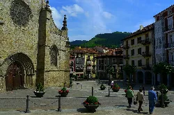 Square with people walking and historic building in Balmaseda.