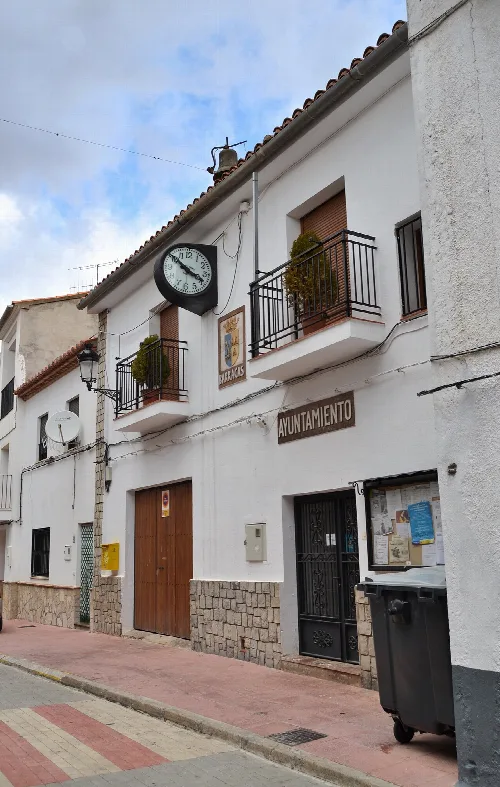 Edificio blanco con reloj y banderín, en la calle principal de Barracas.