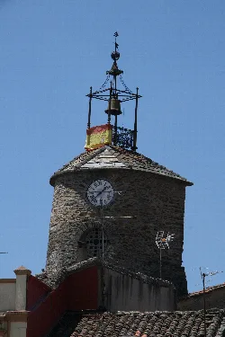Torre de piedra con reloj y campanario en la parte superior.