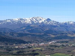Berg mit Schneebedeckter Spitze und grünes Tal im Vordergrund.