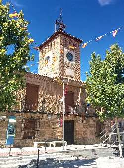 Edificio de la casa consistorial con reloj en la torre y banderines decorativos.