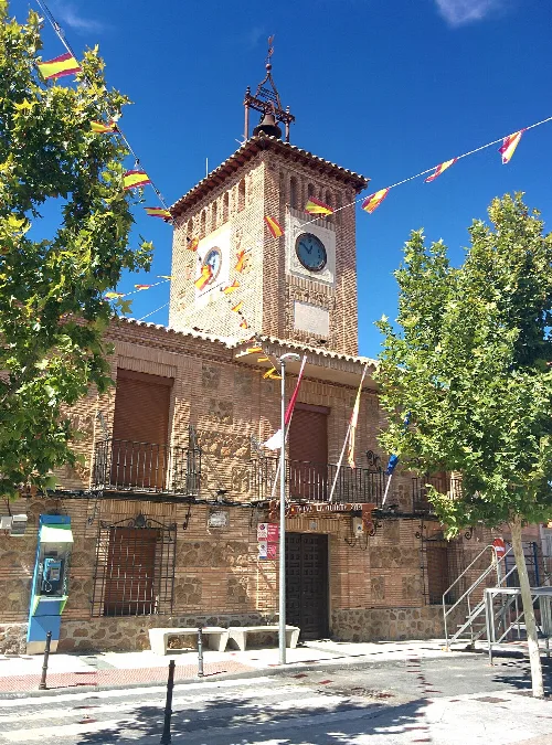 Edificio de la casa consistorial con reloj en la torre y banderines decorativos.