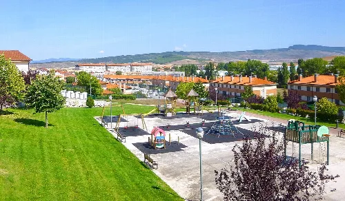 Spielplatz und Park in Beriáin, Navarra, mit Hügeln im Hintergrund.