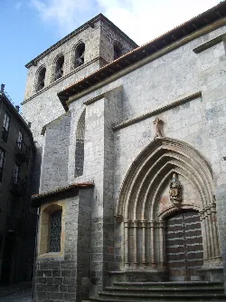 Fachada de una iglesia con entrada gótica y escultura en Arrasate.