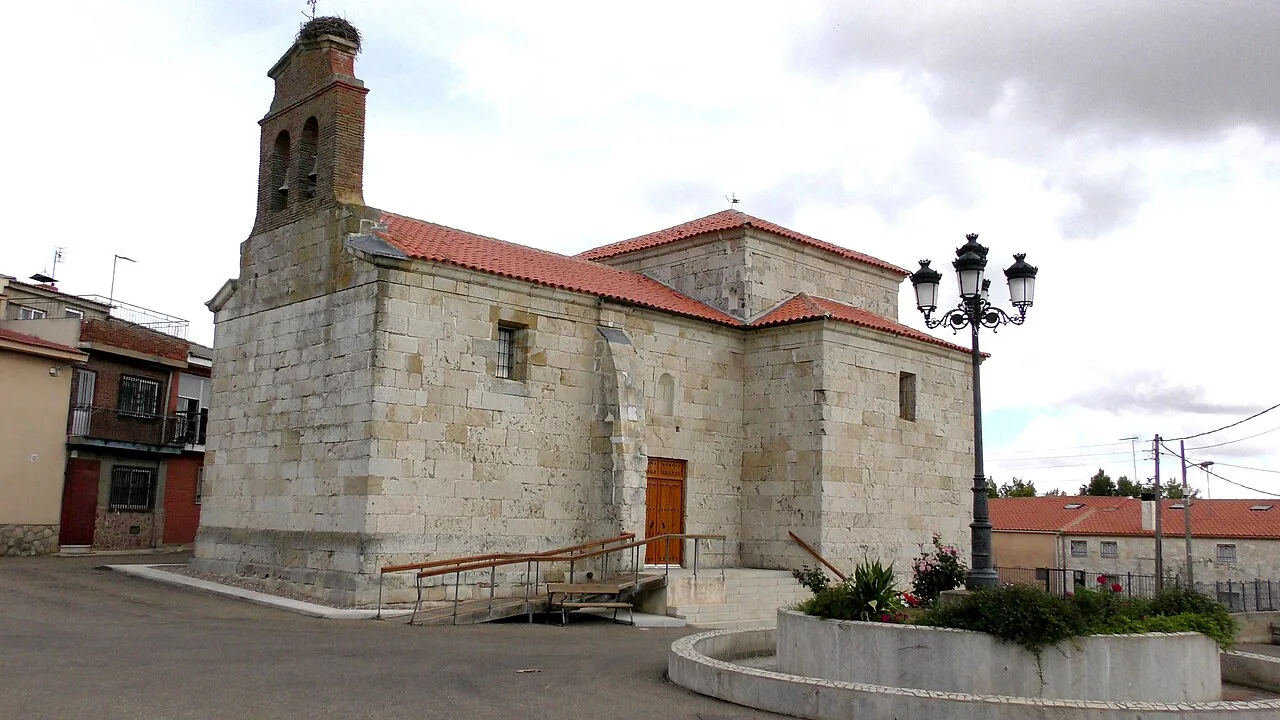 Stone church with bell tower and red tiled roof in Mayalde.
