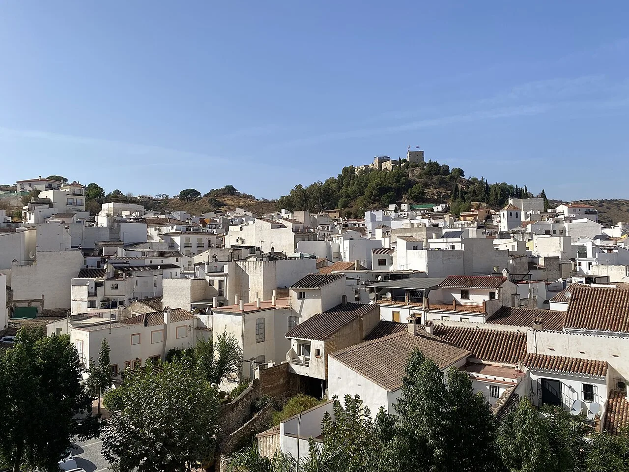Vista de casas blancas en Monda con un castillo en la colina.