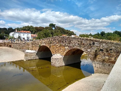 Steinernes römisches Brücke in San Nicolás del Puerto, reflektiert im Fluss.