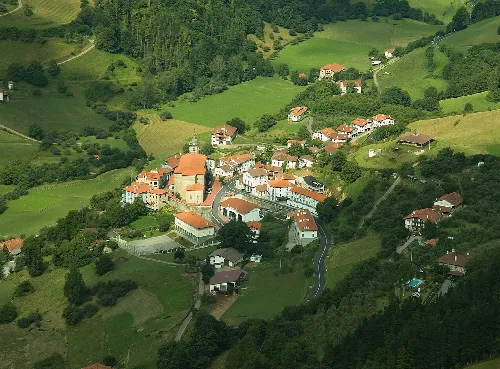 Luftaufnahme eines Dorfes in einem Tal umgeben von Natur.