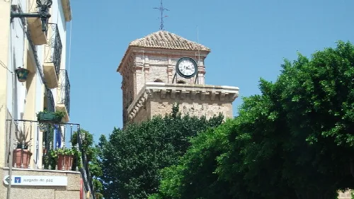 Torre de iglesia con reloj y árboles en Níjar, Almería.