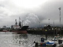 Harbor with ships and boats under cloudy sky in Avilés.