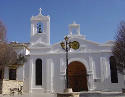 Fachada blanca de una iglesia con torres y farol en primer plano.