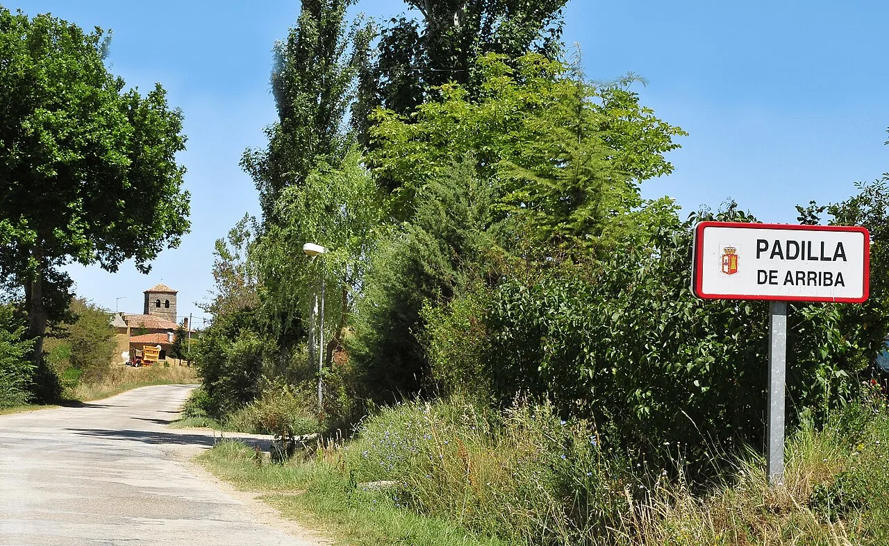 Camino rural con árboles y señal de bienvenida a Padilla de Arriba.